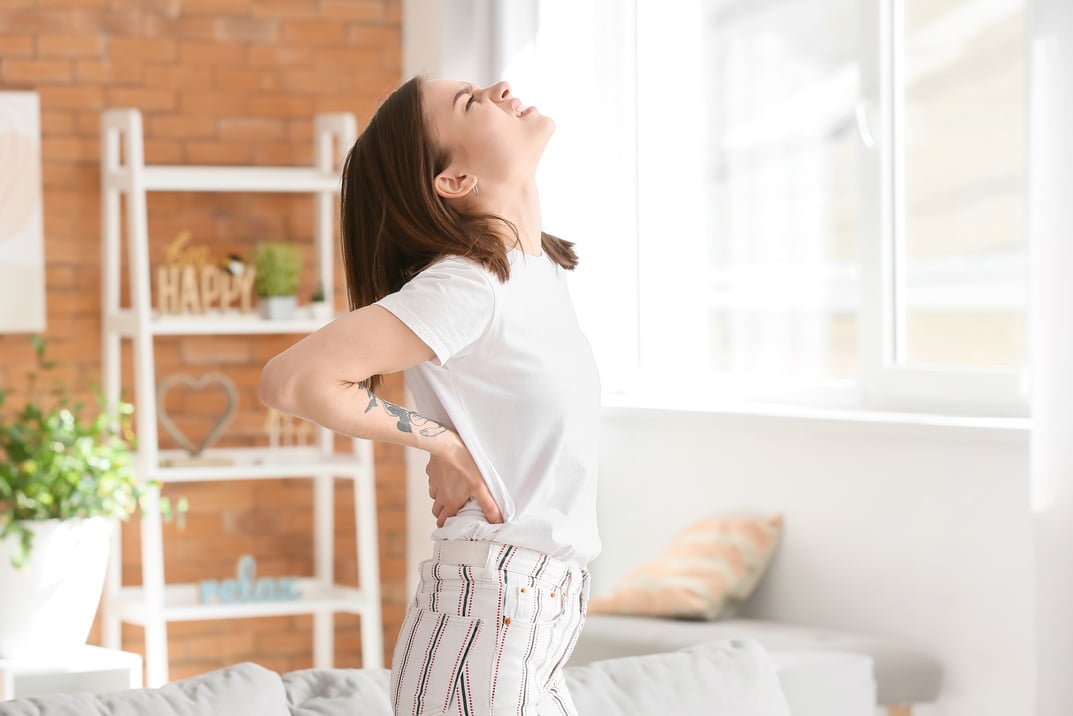 Young Woman Suffering from Back Pain at Home